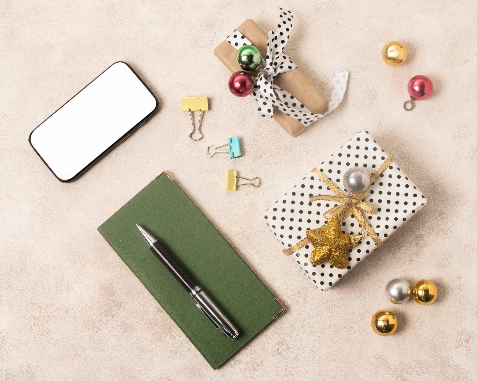 Wrapped gift with brass details beside a green notebook and pen